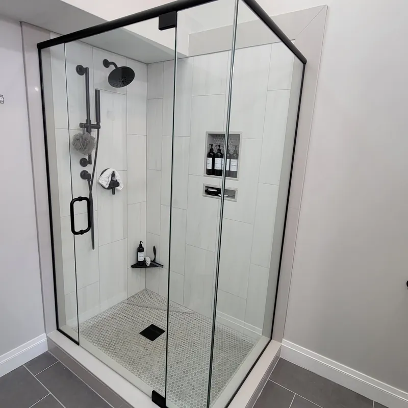A frameless corner shower with a matte black header across the top