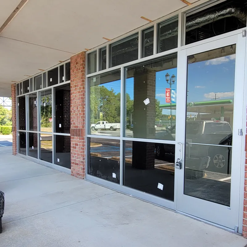 A row of storefront windows and a glass entry door under a covered walkway